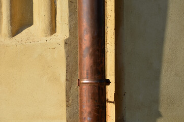 Copper eaves on a beige historic building. They are often stolen. They have a shiny surface and...