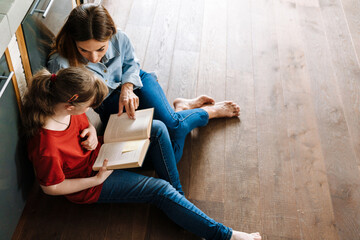 Woman and her daughter with down syndrome reading book