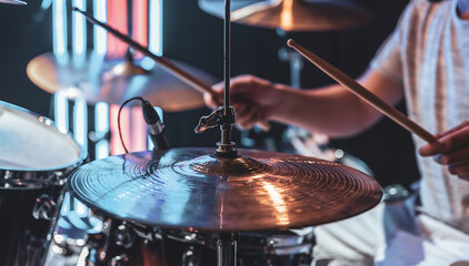 Close-up of a drummer playing a drum cymbal on a blurred background.
