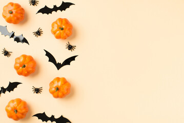 Obraz na płótnie Canvas Top view photo of halloween decorations small pumpkins spiders and bats silhouettes on isolated beige background with blank space