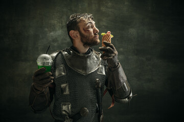 Portrait of one brutal bearded man, medeival warrior or knight with hot dog and cool drink over...