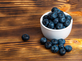 Fresh blueberry in white dish on wooden background copyspace