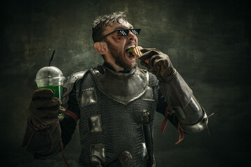 Portrait of one brutal bearded man, medeival warrior or knight with hot dog and cool drink over...