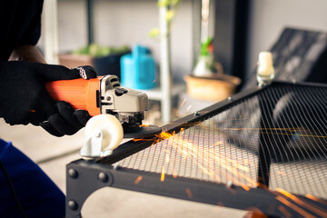 Man using electric grinding on steel table with bright sparks.