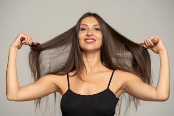 Front view of happy woman brushing her hair with two hair brushes