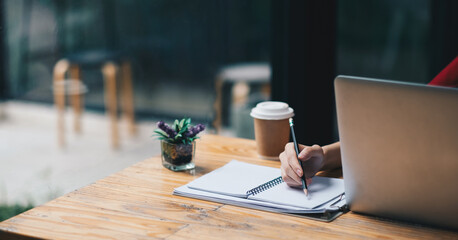 Close up of businesswoman or accountant hand holding pen working on calculator and laptop computer to calculate business data during make note at notepad, accountancy document at office.