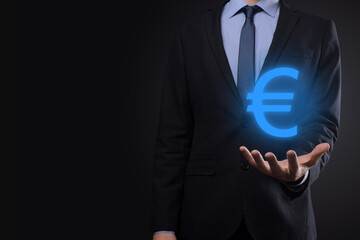 Businessman holds money coin icons EUR or Euro on dark tone background..Growing money concept for business investment and finance