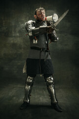 One brutal bearded man, medeival warrior or knight with loudspeaker over dark background.