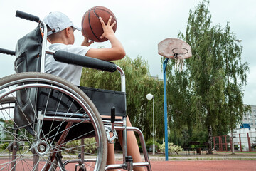 Boy in a wheelchair on the basketball court. Rehabilitation, disabled person, paralyzed, happy disabled child.