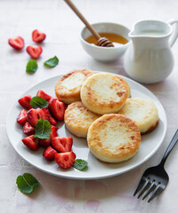Cottage cheese pancakes, ricotta fritters on ceramic plate with  fresh strawberry.