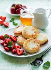 Cottage cheese pancakes, ricotta fritters on ceramic plate with  fresh strawberry.