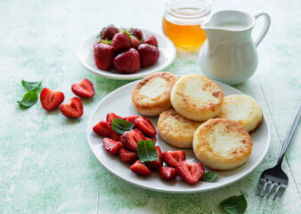 Cottage cheese pancakes, ricotta fritters on ceramic plate with  fresh strawberry.