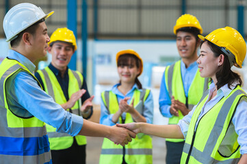 Factory employee of engineers, foreman, technicians and staff. Wear a mask, hard hat, and vest. shake hands to make a deal or celebrate success in the organization or warehouse. Teamwork concept.