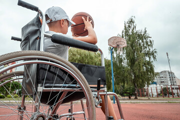 Boy in a wheelchair on the basketball court. Rehabilitation, disabled person, paralyzed, happy disabled child. - obrazy, fototapety, plakaty