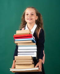 Smiling funny little schoolkid girl with backpack hold books on green blackboard. Childhood lifestyle concept. Education in school. Knowledge day.