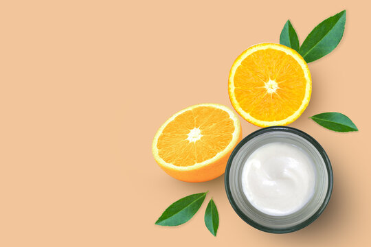 Orange skin care moisturizing cream in glass jar with fresh orange fruit slice isolated. Natural org