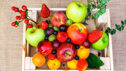 Summer fruit, berry assortment. Big apple, plum, apricot, grape and strawberry. Colorful berries in wooden crate on the table.