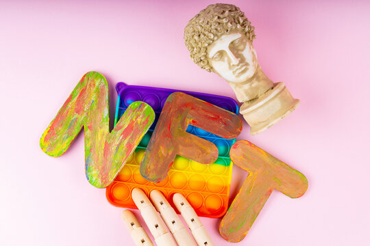 NFT Non-Fungible token. Concept for blockchain system. Classical statue and Pop it toy on a pink background. Crypto art concept with an artificial hand
