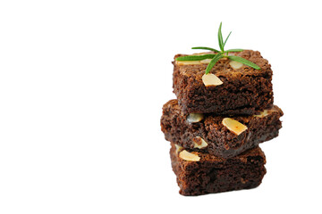 pieces of fresh homemade chocolate brownie, square shape, and sliced almond on top decorated with small rosemary branch isolated on white background