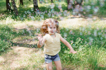 cute baby girl catches a lot of soap bubbles on a summer day