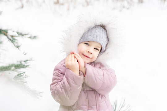 portrait of a cute little girl in a fur hood in a snowy winter