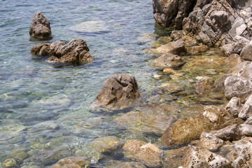 Big stone close-up on the background of the sea. Group of large gray stones. Boulders are standing in the beautiful water. Rocky seaside coast.