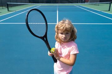 Child with tennis racket and ball on tennis court outdoor. Sport exercise for kids. Summer activities for children. Training for young kid