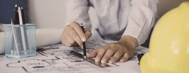 Engineer and Architect concept, Man uses a ruler to measure the floor plan on the blueprint,...