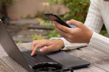 woman relax using mobile smart phone and work on laptop computer at cafe outdoor garden nature background