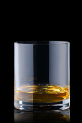 Portion of bourbon in transperent glass isolated on black