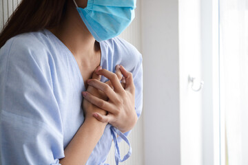 female patient wearing a mask have heart pain Put your hand on your chest to reduce the pain....