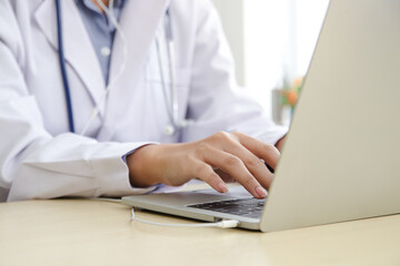 Fototapeta premium Asian female doctor online video call Check the symptoms with the patient via the Internet. on a laptop computer. The concept is connected to communication through online technology.