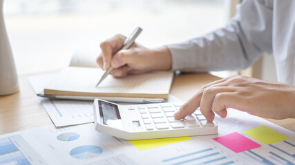 Head of accounting is recording the company's financial growth statistics using graphs as a reference for reviewing and analyzing the results, Taking notes and analyzing data graphs in office.