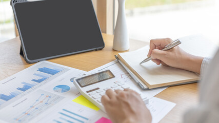 Head of accounting is recording the company's financial growth statistics using graphs as a reference for reviewing and analyzing the results, Taking notes and analyzing data graphs in office.