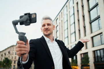 An entrepreneur, a man in a business suit, records a video near the new office. The lawyer...