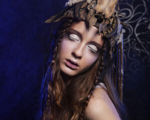 High fashion model with creative hairstyling and bright make up over dark background