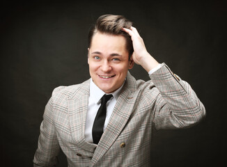 Stylish man wearing suit and tie posing on black background