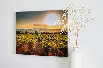 Canvas photo print with gallery wrap and flowers in vase, interior decor. Landscape photography hanging on white wall