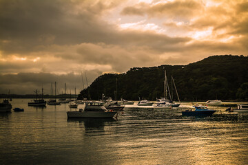 Flashes of sunset colours reflected in calm waters of a small harbour. Fishing and sailing boats...