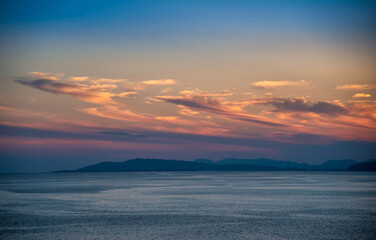 Beautiful cloudscape and dramatic sunset over mountain and sea.