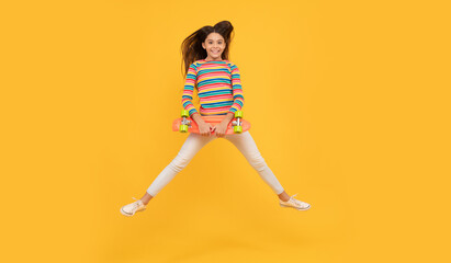 Fototapeta na wymiar skateboarding. happy child jump with penny board. teen girl on yellow background.