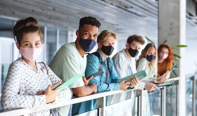 University students standing and looking at camera indoors, coronavirus and back to normal concept.