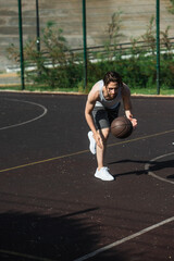 Young sportsman playing basketball on playground outdoors