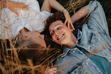 Top view of young couple on a walk in nature in countryside, lying in long grass.