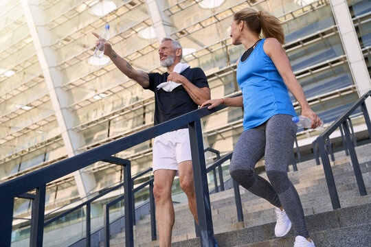 Low Angle View Of Mature Couple, Man And Woman In Sportswear Walking Down The Stairs After Working Out Together Outdoors