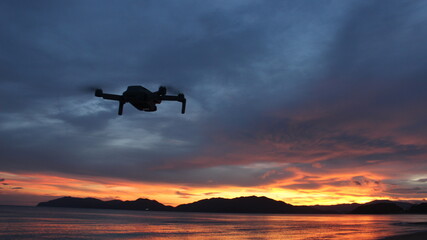 夕日の瀬戸内海を飛行するドローンのシルエット