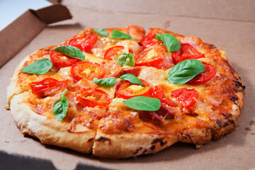 Pizza with tomatoes, sausages and cheese in a cardboard box