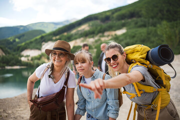 Happy multigeneration family on hiking trip on summer holiday, pointing at something.