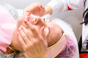 Happy and relaxed woman on cosmetology procedures, massage and applying face cream.