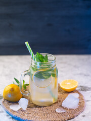 Icy summer lemon mojito on a stone table with blue lighting . Detox water with lemon and mint